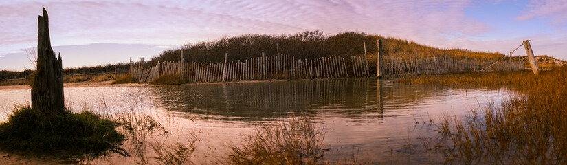 Flooded beach yard after winter rain in Cape Cod coastal village with rustic snow fens and bush hills in the water, Massachusetts, USA