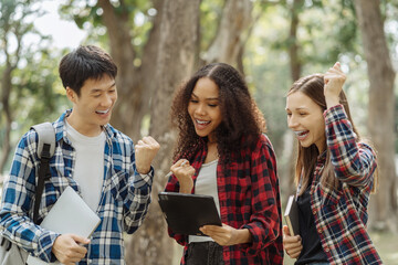 Happy group of college students use laptop feel excited overjoyed triumph with good news over smartphone or Tablet.