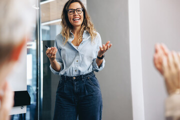 Successful team leader receiving a round of applause from her colleagues after her presentation