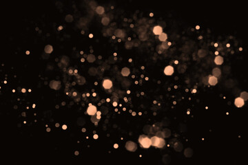 Peach fuzz blurred abstract bokeh lights on black background. Snowy shiny glitter sparkle stars for...