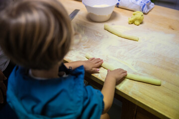Fototapeta na wymiar A kid play preparing gnocchi in a kitchen