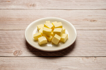 Fototapeta na wymiar Butter cubes sliced, dairy product, cooking ingredient. Wooden background