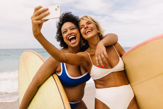 Best friends taking a selfie on a fun surfing vacation at the beach