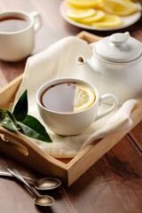 Drinking tea, white ceramic cup and tea pot with black tea and lemon slice. 
