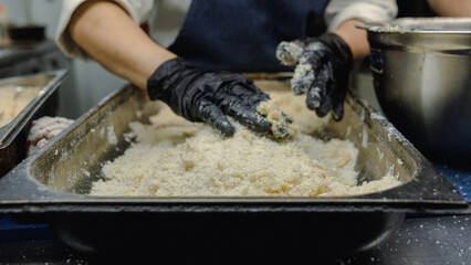 Cocinero empanando pollo en la cocina de un negocio local 