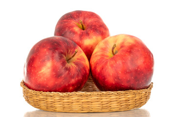 Three ripe juicy apples on a straw plate, macro, isolated on white background.