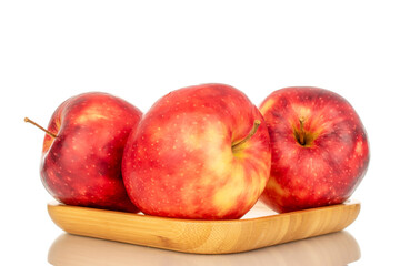 Three ripe juicy apples on a bamboo plate, macro, isolated on white background.