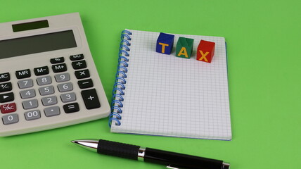 Single Word Taxes On Wooden Block, Over A Notebook With Calculator And Ballpoint Pen.