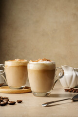 Two glass cups with coffee drink, latte with milk foam and cinnamon 