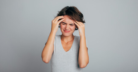 Close up photo of young woman feeling headache, migraine or being ill with short hair in t-shirt...