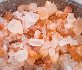 Himalayan pink salt in a spoon on a salt background close-up. Top view