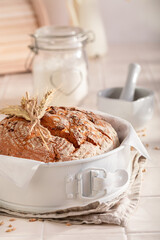 Healthy loaf of round bread with grain and ears.