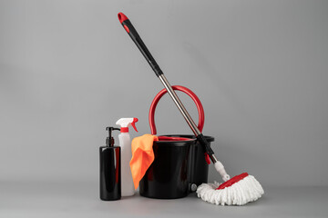 Cleaning concept mop and bucket. Cleaning products and spin mop with red details on the floor in...