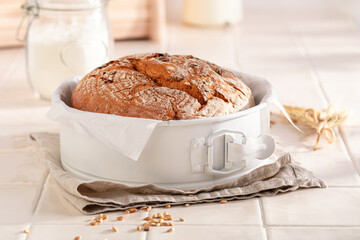 Healthy loaf of round bread in a bright spring kitchen.
