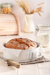 Homemade loaf of round bread with grain and ears.