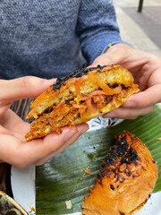 Primer plano de manos de hombre sujetando un sandwich de Cochinita Pibil