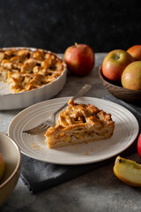 Slice of apple pie, homemade fresh fruit pie with red apples, dark background