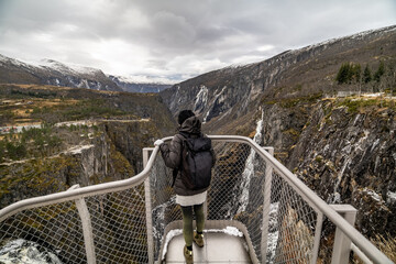 woman with no face with backpack looking at Vøringfossen waterfall from viewpoint
