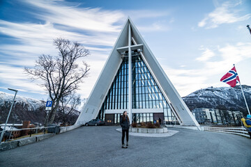 young pretty woman poses in front of arctic Cathedral church in tromso during winter © Sid Smith