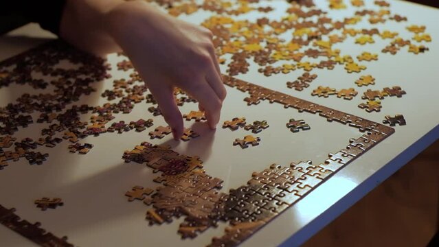Depression concept. Lone woman trying to finish jigsaw puzzle. Hands close up