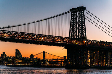 Illuminated bridge over river in evening city