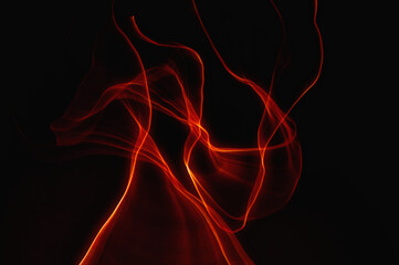Fiery dance of red lines on a black background, images emerge from the chaos of movement, abstract photography, created using intentional camera movements