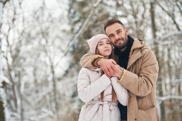 Cheerful facial expression. Lovely couple have a walk in the winter forest