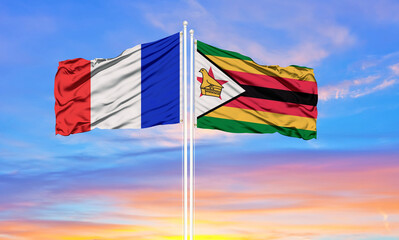 france and zimbabwe  two flags on flagpoles and blue cloudy sky . Diplomacy concept, international relations