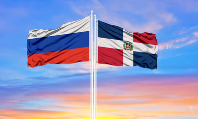 Russia and Dominican Republic two flags on flagpoles and blue sky.