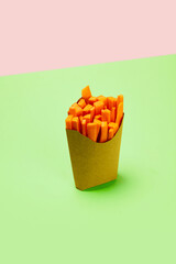 Cut, fresh carrots placed into carton packaging for fries against green background. Concept of healthy food, nutrition, diet, organic products, diet, vegetable vitamins. Poster, ad