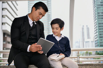 Caucasian father and son using tablet in city.