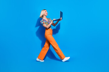 Full length profile photo of gorgeous person walking use laptop coworking empty space isolated on blue color background