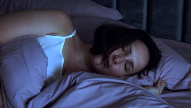 Tired young woman going to sleep into the bed at night close up