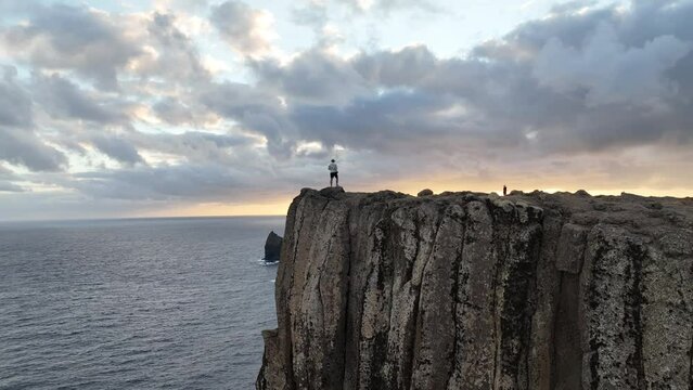 Drone shot of adult man stands on a coastal cliff at Ponta de Sao Lourenco in Canical town, Madeira