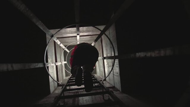 Slow motion low angle footage of a man coming down on a vertical staircase with industrial parapets