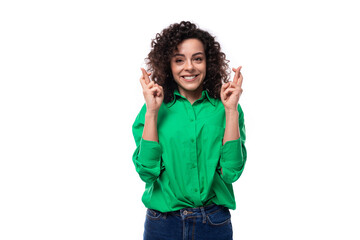 Fototapeta premium a young woman with black curly hair dressed in a green blouse crossed her fingers