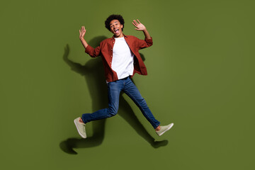 Full length photo of nice young man jumping running have fun dressed stylish brown garment isolated on khaki color background