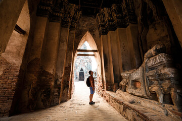 Fototapeta na wymiar Tourist male shoulder bag walking near ancient ruined stupa with photo camera in Ayutthaya