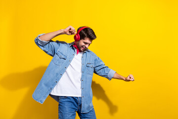 Photo portrait of nice young man have fun dancing headphones dressed stylish denim garment isolated on yellow color background