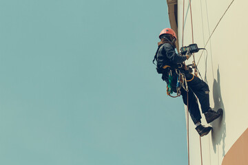 Male worker rope access height safety inspection of thickness storage oil and gas tank