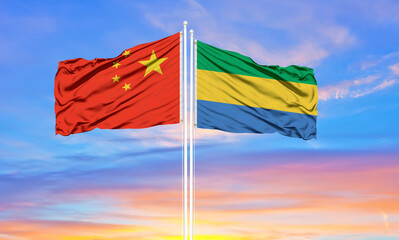Flag of China and Gabon waving in the wind against white cloudy blue sky together. Diplomacy concept, international relations