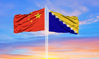 China and Bosnia and Herzegovina two flags on flagpoles and blue cloudy sky . Diplomacy concept, international relations