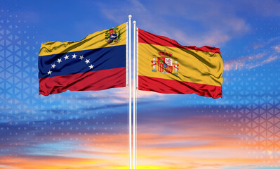 Venezuela and Spain two flags on flagpoles and blue cloudy sky . Diplomacy concept, international relations