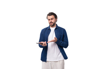 a young well-groomed brunette guy in a casual blue shirt holds a mobile phone in his hands and carefully studies the information