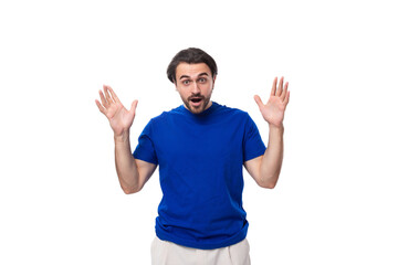 Fototapeta premium young brunette man with a beard dressed in a blue t-shirt thinks about solving problems on a white background