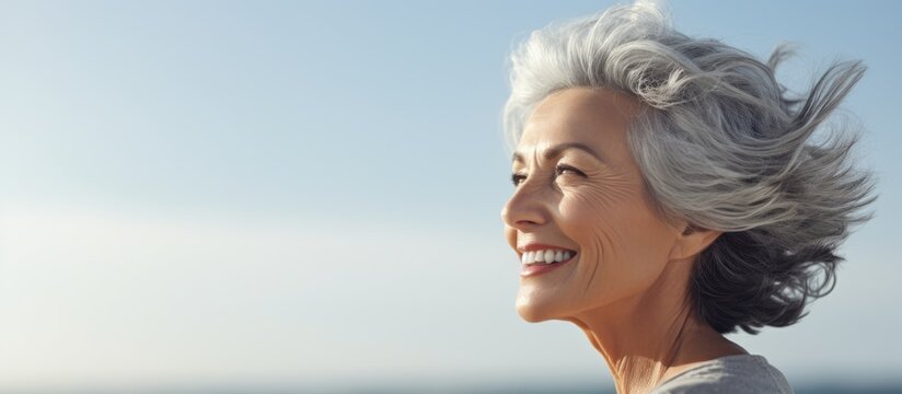Middle age grey haired woman smiling confident relaxed with hands on head at seaside. Website header. Creative Banner. Copyspace image