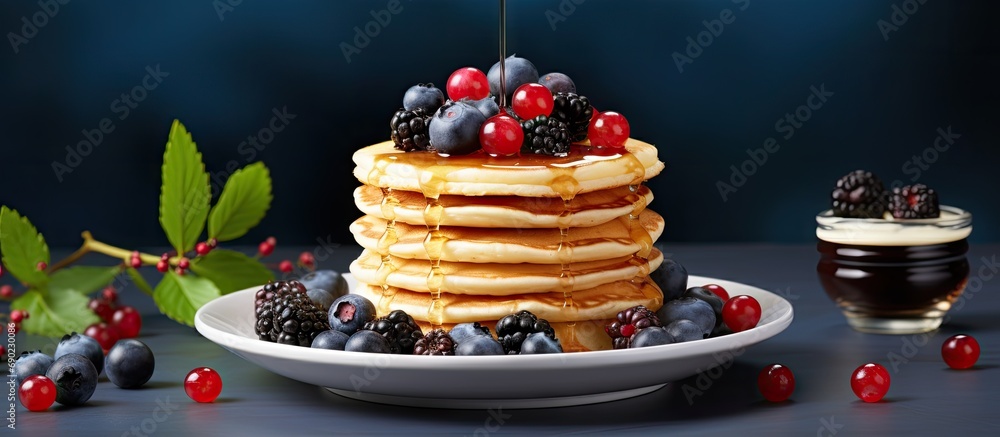 Poster pile of pancakes with red currants blueberries and honey on a grey plate with fork. website header. 
