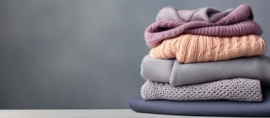 Pile of folded knitted warm women sweaters and scarves on gray background Soft comfortable cozy...