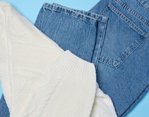 Blue jeans and white knitted sweater on a blue background