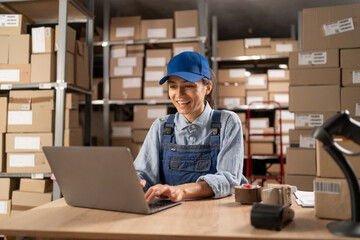 Employee in retail shop's warehouse. Small Business Owner working on laptop, preparing and packing...